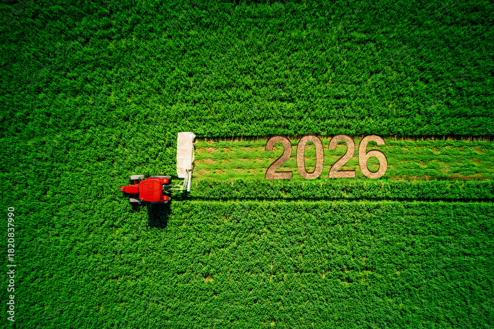 Fototapeta premium Happy new year 2026 agriculture conccept. Tractor mowing green field, aerial top view holiday background