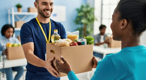 Smiling male volunteer in blue hands a packed food donation box to a grateful woman, embodying essential community support and compassionate giving