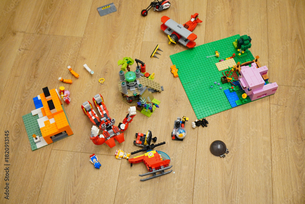 Obraz premium Colorful toy building blocks scattered on a wooden floor, overhead shot