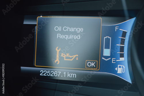 Digital Car Dashboard Displaying Oil Change Required Maintenance Warning with Wrench and Oil Can Symbol, Odometer Mileage, Fuel Gauge, and Headlight Indicators