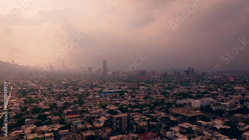 Aerial panoramic drone view of Monterrey city sprawl covered in heavy smog and atmospheric haze at sunset. Urban pollution concept.