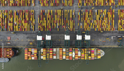 Aerial view of a ship being unloaded by cranes amidst a sea of colorful containers creating a vibrant mosaic of global trade, Antwerp, Vlaanderen, Belgium.