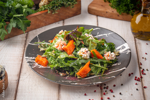 Vibrant pumpkin salad with mixed greens, seeds and creamy toppings served on a dark rustic plate