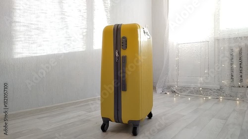 A yellow suitcase stands in a bright room for travel