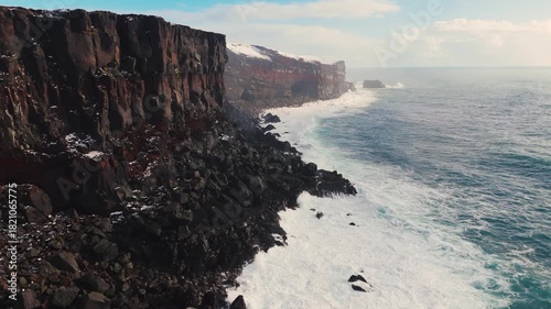 Wallpaper Mural Aerial view of storm ocean waves crashing against snowy coastal cliffs at winter sunrise. The Icelandic plateau reveals striking, martial red mineral cliffs contrasted against the icy landscape Torontodigital.ca