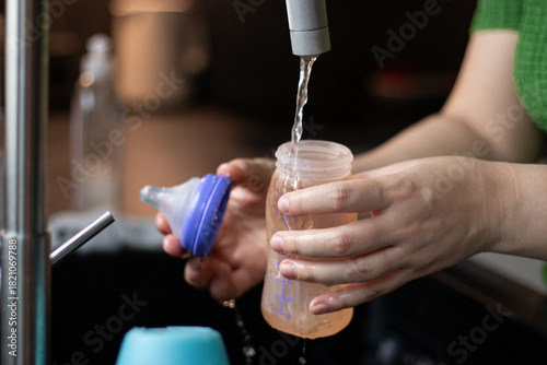 Close up of a woman cleaning a bottle and nipple for baby milk with a brush