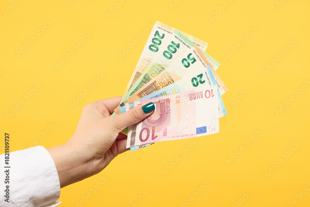 custom made wallpaper toronto digitalWoman hand holding euros banknotes isolated on yellow background. Finance concept.