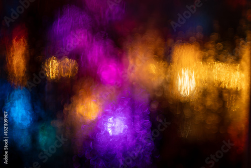 Abstract lights blurred through wet textured surface, vibrant colors and atmospheric glow