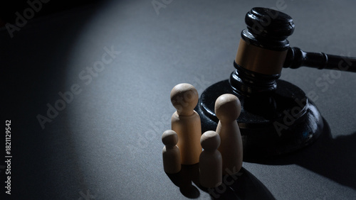 A wooden gavel next to a group of four wooden peg dolls. Family law, legal justice, child custody, social policy, and family protection concept.