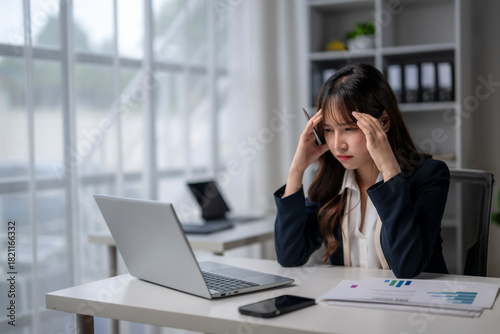 Stressed businesswoman having headache while working on laptop in office