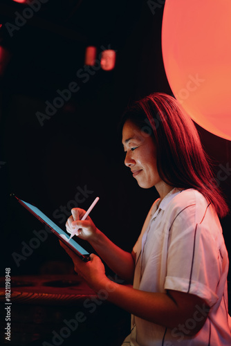 Obraz na plátně Woman focused on digital sketching with stylus on tablet, immersed in creative tech-driven workflow, reflecting calm confidence and modern artistic connection