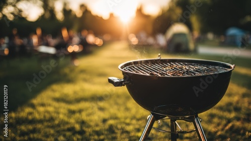 Outdoor charcoal kettle grill cooking food over hot embers during sunset at a gathering