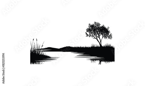 Black silhouette of a lone tree and reeds on a riverbank with water reflections