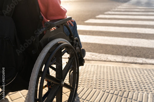 Close-up of an unrecognizable person in a wheelchair waiting at a pedestrian crosswalk