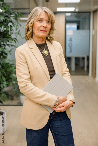Mature woman standing in office holding tablet
