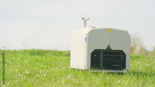 A drone launch box sits on a grassy field, equipped with technology and sensors from which a drone can be deployed.