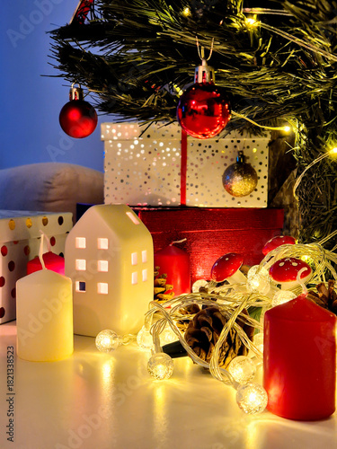 Christmas decorations: gifts wrapped in paper, candle, Christmas baubles and ornaments, and a garland glowing with warm light.