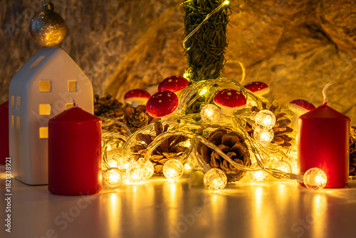 Christmas decorations: gifts wrapped in paper, candle, Christmas baubles and ornaments, and a garland glowing with warm light.