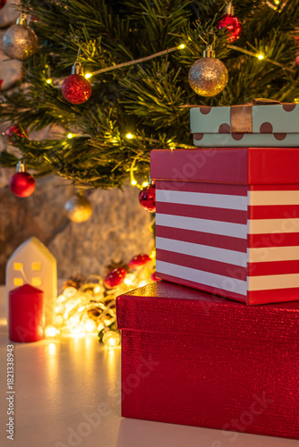 Christmas decorations: gifts wrapped in paper, candle, Christmas baubles and ornaments, and a garland glowing with warm light.