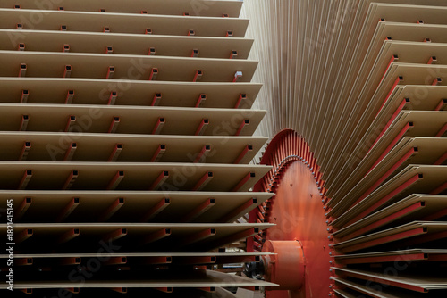 Large stacks of wood panels or MDF sheets arranged inside an industrial production facility. The image shows part of the machinery used to process and dry wood panels.