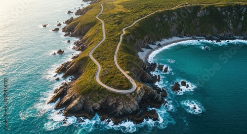 Aerial view captures winding coastal roadway traversing dramatic green headland beside turquoise ocean waters