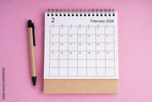 February 2026 desk calendar with eco friendly pen on a pink background, representing planning, scheduling, and organization in a clean minimalist workspace