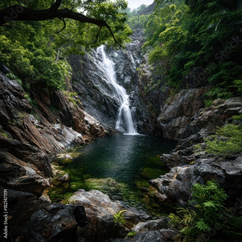 Serene Waterfall Cascading into a Lush Pool in a Rocky Forest.