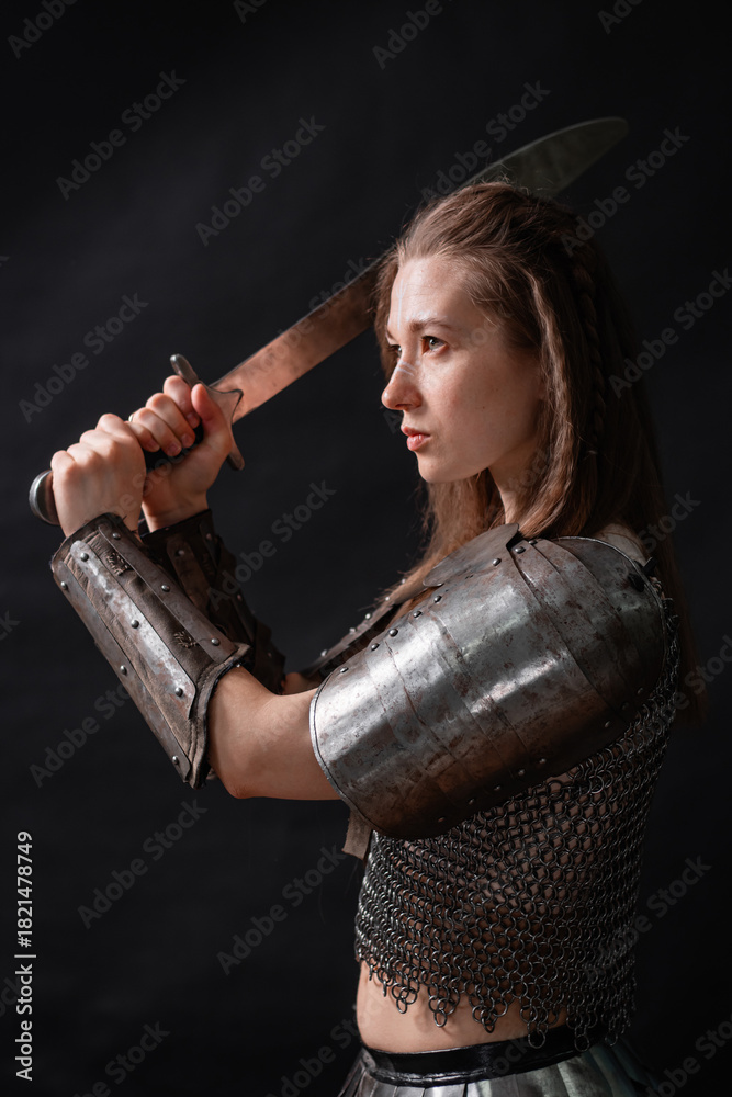 Obraz premium Portrait of a young woman, fantasy warrior in armor with a sword in her hands isolated on a dark background.