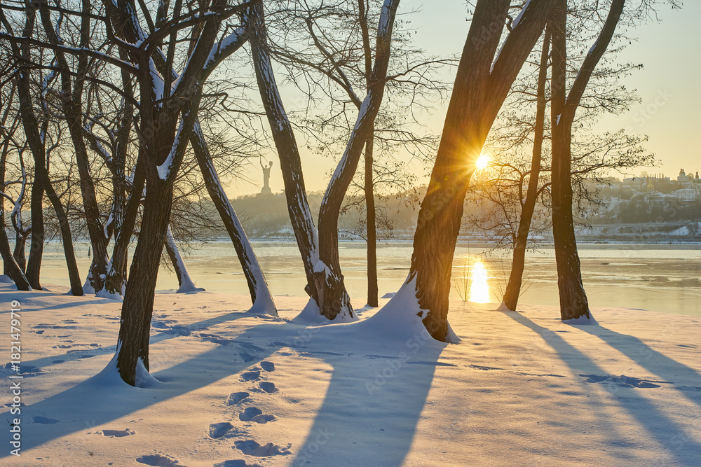 Obraz premium Sunny winter landscape with trees and distant monument.