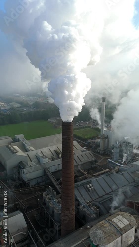 Drone aerial cinematic footage of sugar factory highlighting silos chimney stacks smoke plumes and pollution in foggy winter Bury Saint Edmunds UK