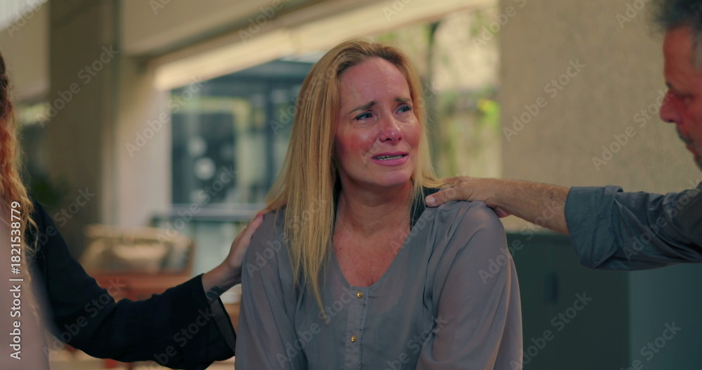 Fototapeta premium Crying woman comforted by group members during emotional moment in therapy session, expressing pain while receiving compassionate support and presence