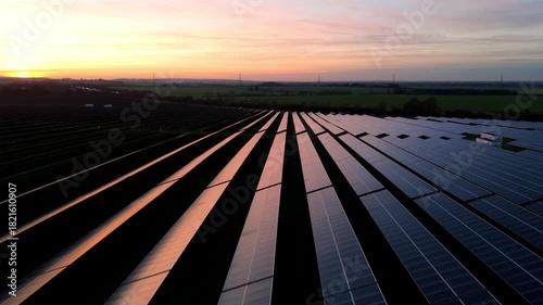 Cinematic drone footage of solar panels producing renewable electricity at golden red winter sunset in countryside near Newmarket UK