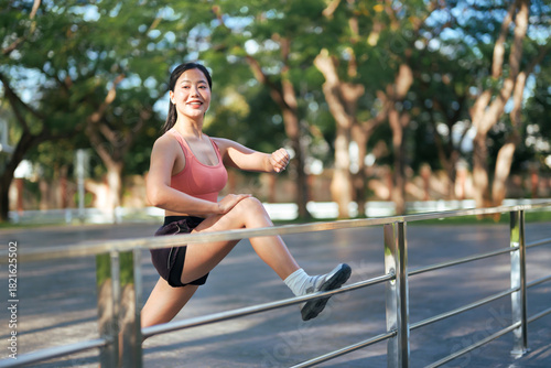 Young Asian woman stretching legs in park outdoor