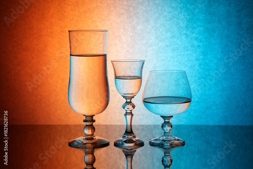 Three glass goblets on a colored gradient background