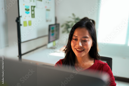 Young Asian woman smiling working on computer in office Free Download Young Asian woman smiling working on computer in office - GFXLoad