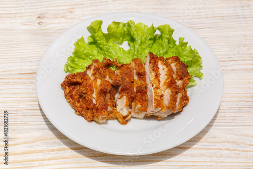 Poulet croustillant pané sur assiette blanche avec feuille de salade. Cuisine asiatique. Traiteur asiatique.