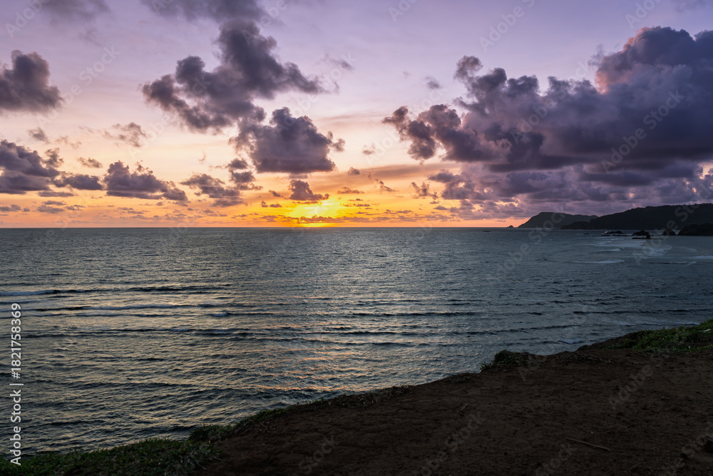 Fototapeta premium Lombok Indonesia – Bukit Merese cliffs, ocean views and a vibrant sunset on the rugged coastline.