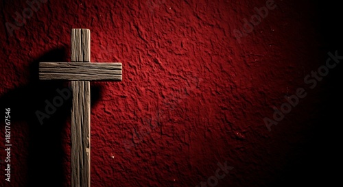 Rustic wooden cross against a textured deep red background with dramatic lighting