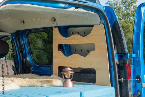 gemütlicher Minicamper steht im Grünen mit Stühlen davor 