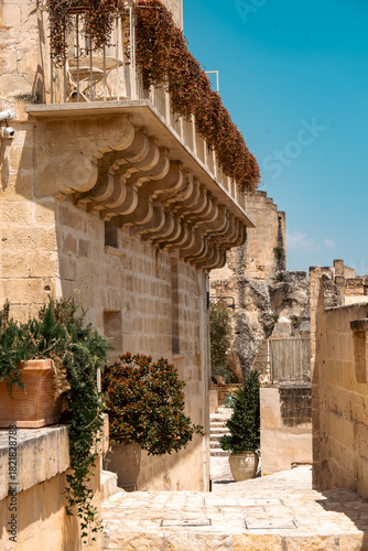 Narrow Stone Alleyway and Balcony with Floral Decoration in Sassi di Matera, Italy