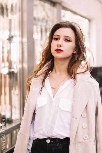 Elegant woman in stylish coat standing on city street with handbag