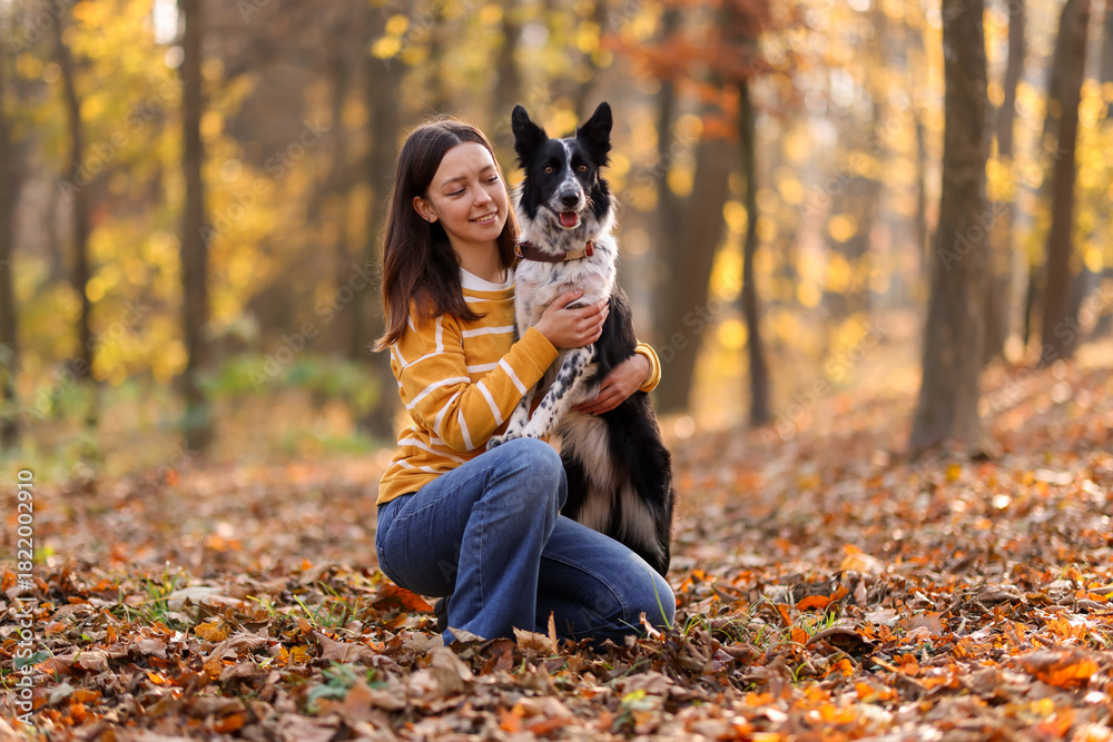 Obraz premium Woman walking her cute dog in autumn park