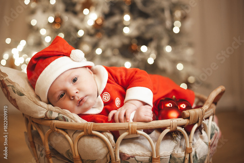 Little girl lays on a holiday background in Santa costume