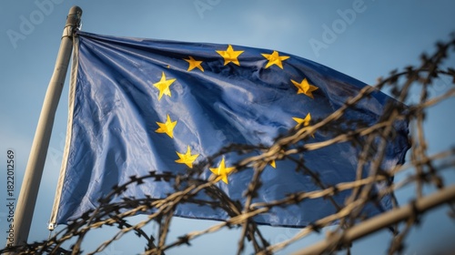European Flag Displayed Against a Barbed Wire Fence Symbolizing Confinement and Restriction in a Stark Landscape