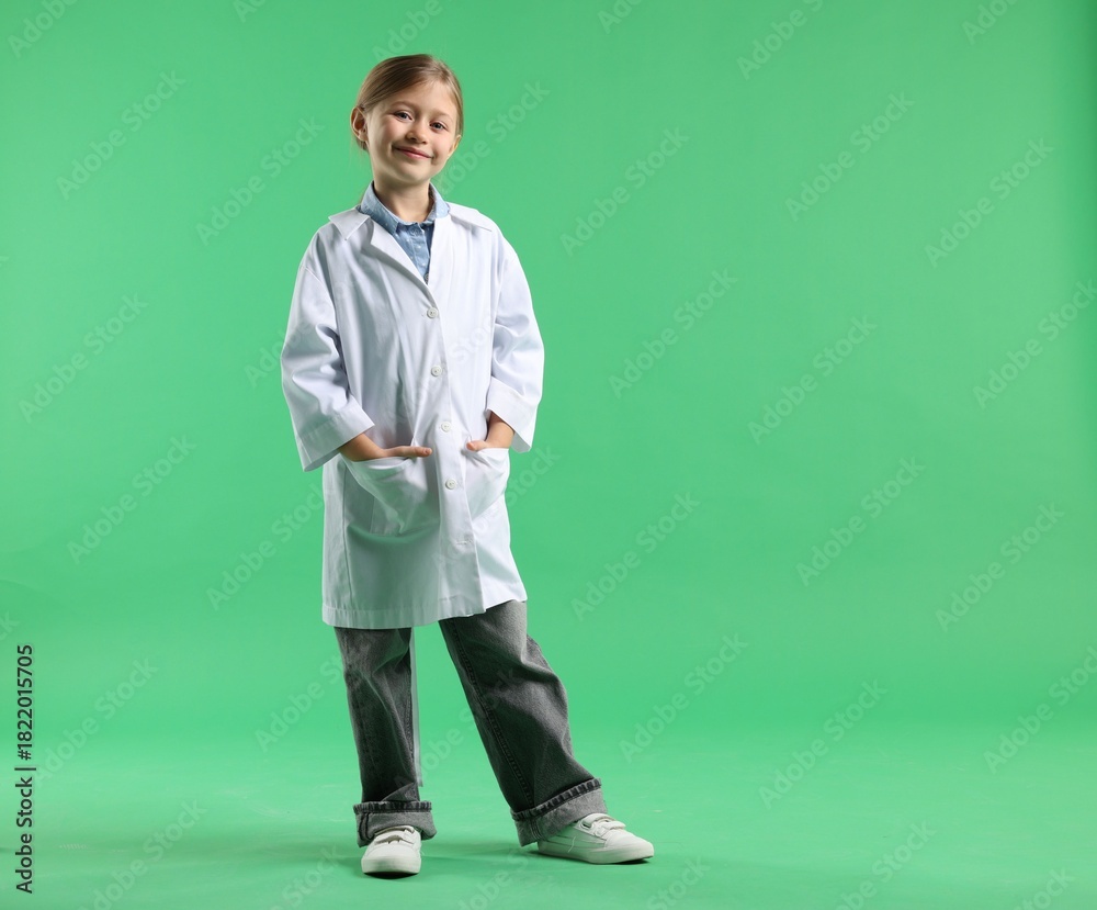 Obraz premium Cute little girl in laboratory coat on green background, space for text. Child and science