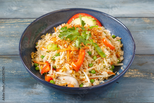 Khao Pad nature avec oignons, pousses de soja, carottes et coriandre dans un bol bleu, cuisine thaïlandaise, fond bleu rustique