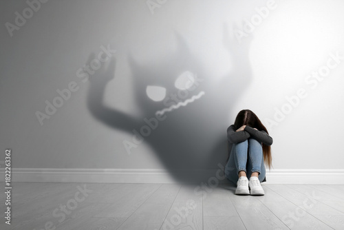 Scared girl and demon coming from her shadow. Phobia, suffering from pathological fear