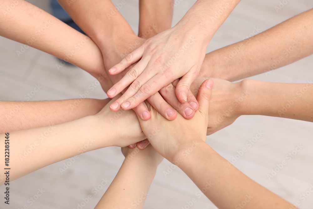Obraz premium Team of volunteers stacking hands indoors, above view