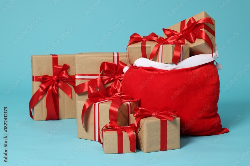 Fototapeta premium Santa Claus bag with Christmas gifts on light blue background