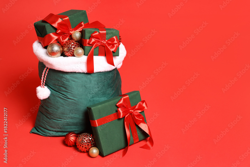 Naklejka premium Santa Claus bag with Christmas gifts and balls on red background, space for text